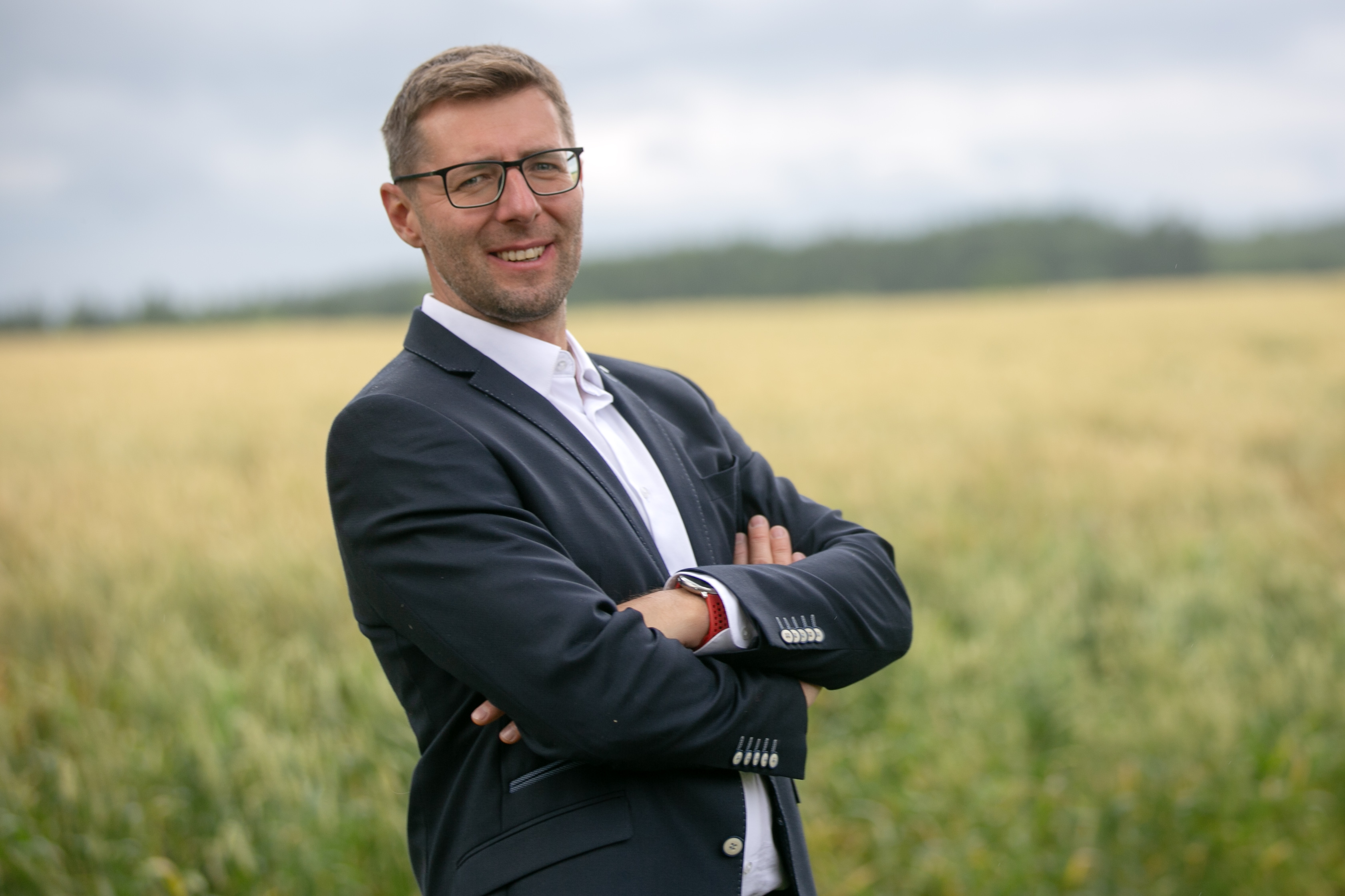 Michal Karný, autor Pan tonalita, stojí se zkříženýma rukama na poli